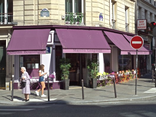 The bakery around the corner from my apartment has hung a new purple awning and put out multicolored tables and chairs.  Today a lovely lady in a purple suit adds a decorative touch.